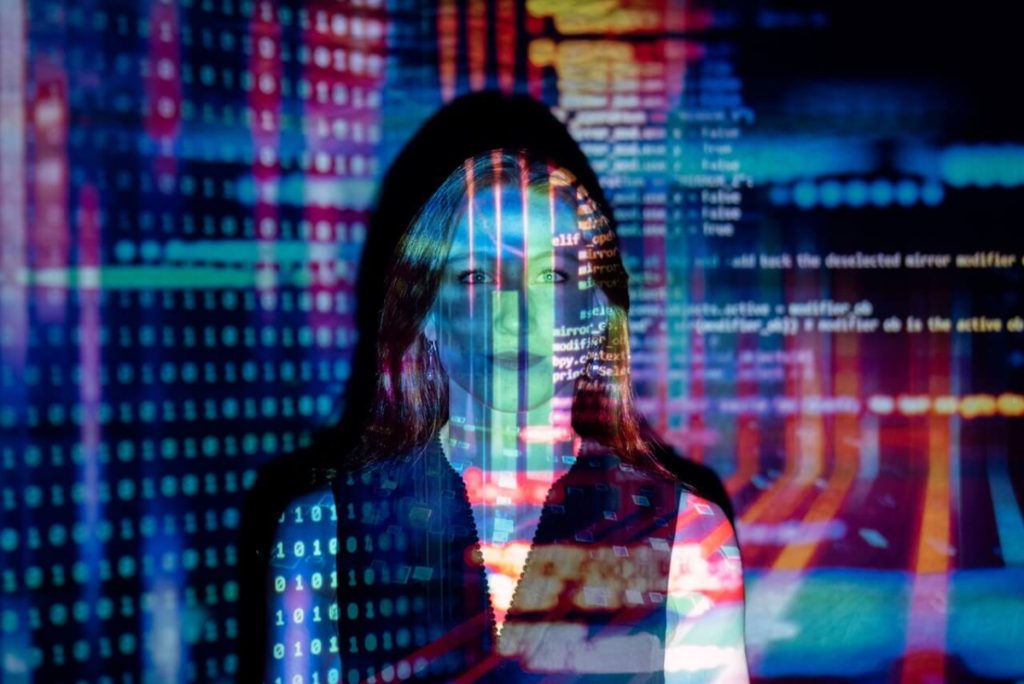 colorful code projected onto woman's face - women's history month cyber security resources for women