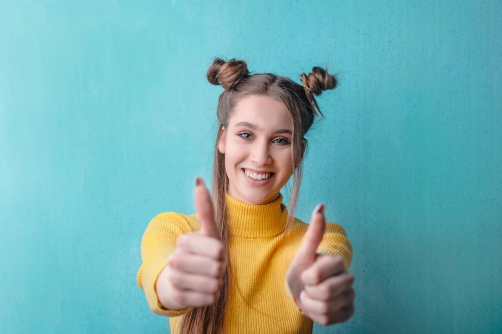 Woman in bright yellow shirt in front of teal background with thumbs up - Cyber Security Resources for Women